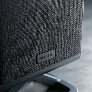 Macro detail of the Sharp HT-SPR52021-BK wireless speaker featuring premium black fabric mesh.