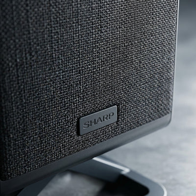 Macro detail of the Sharp HT-SPR52021-BK wireless speaker featuring premium black fabric mesh.